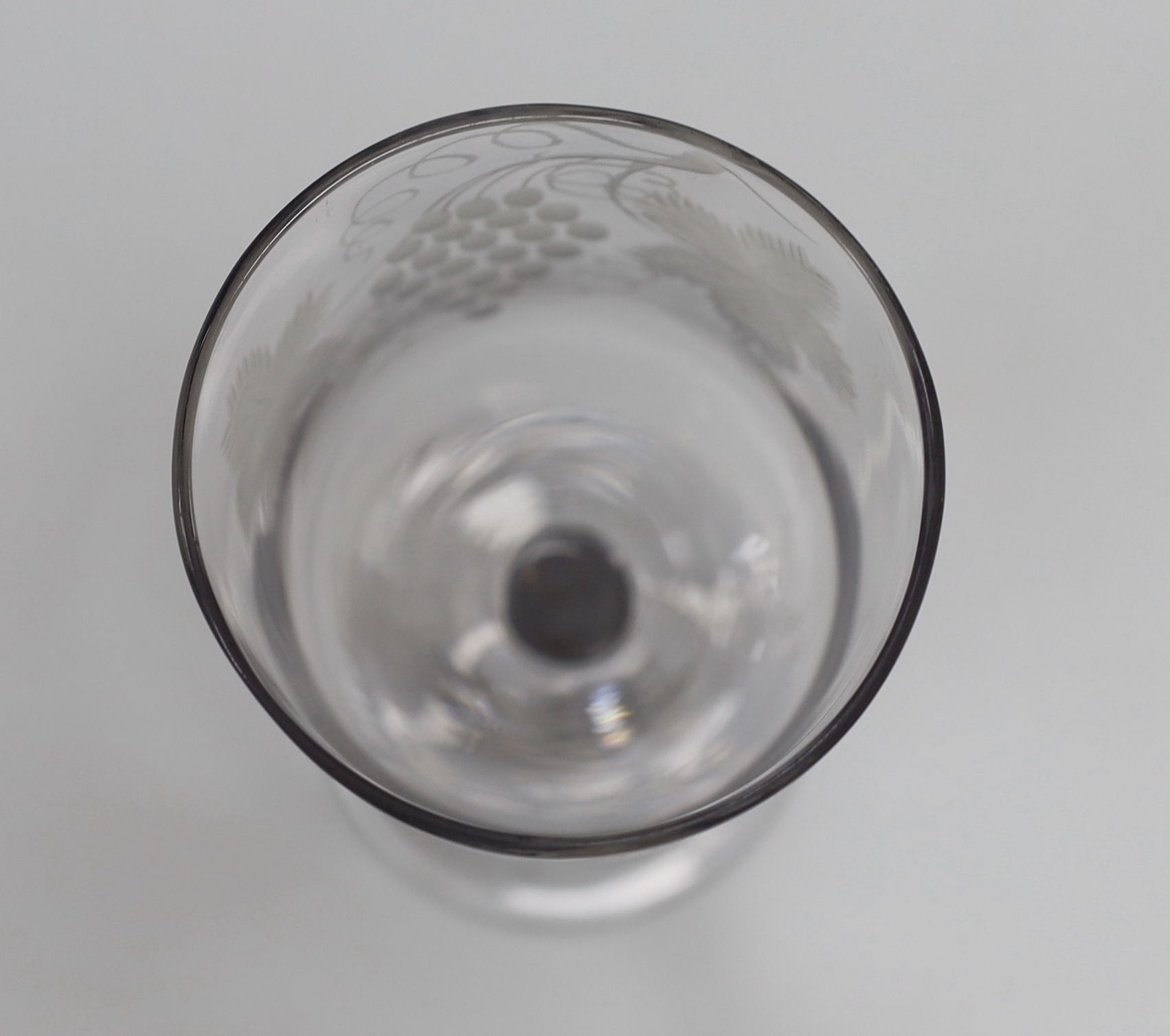 An English lead crystal goblet, c1740-50, ogee bowl with tool marks, engraved fruiting vines and a bird, with a plain stem, conical foot and rough pontil, 19.4cm